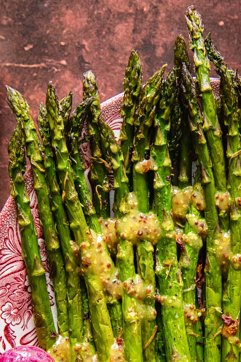 top down view of roasted asparagus with mustard vinaigrette on a platter