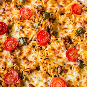 sausage pasta baked with cherry tomatoes on top in round pan