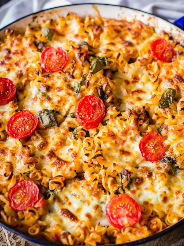 sausage pasta baked with cherry tomatoes on top in round pan