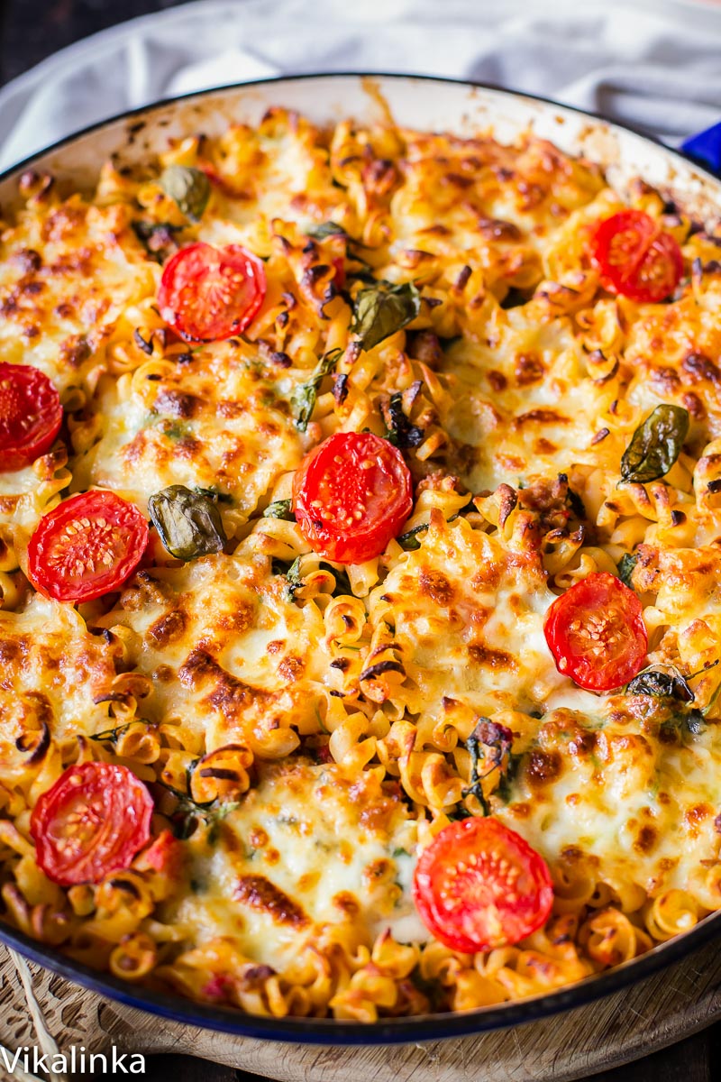 sausage pasta baked with cherry tomatoes on top in round pan