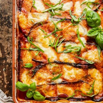 top down view of eggplant parmesan in a rectangular pan on dark background