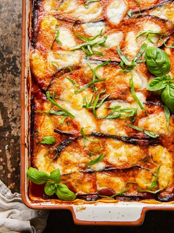 top down view of eggplant parmesan in a rectangular pan on dark background
