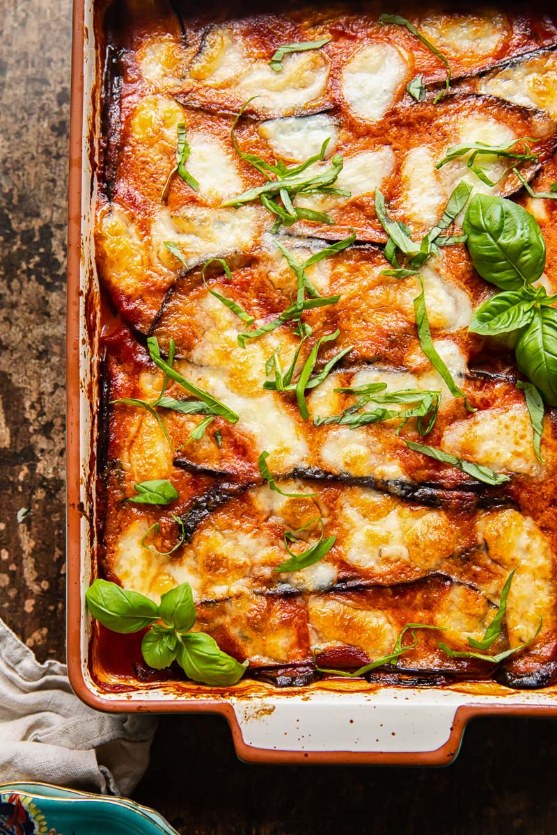 top down view of eggplant parmesan in a rectangular pan on dark background