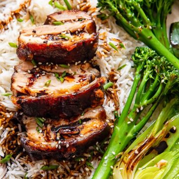 sliced pork belly on top of rice, tenderstem broccoli and bok choy