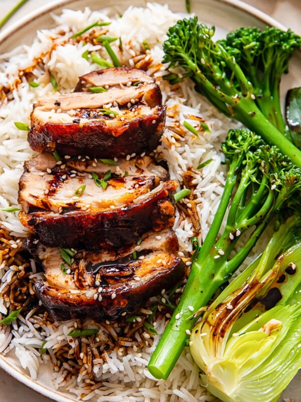 sliced pork belly on top of rice, tenderstem broccoli and bok choy
