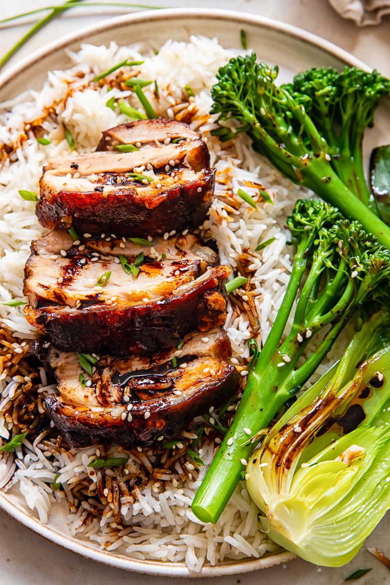 sliced pork belly on top of rice, tenderstem broccoli and bok choy