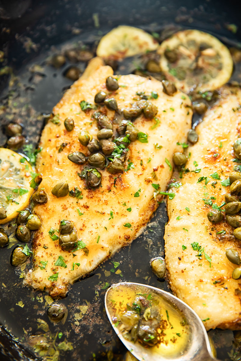 sole fish in lemon butter sauce with capers in cast iron pan