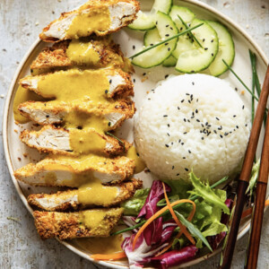 Chicken katsu curry on a plate with rice and vegetables