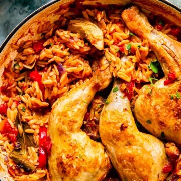 chicken legs on top of orzo in a pan.