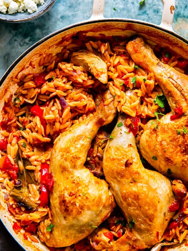 chicken legs on top of orzo in a pan.