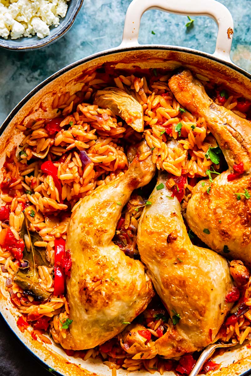 chicken legs on top of orzo in a pan.