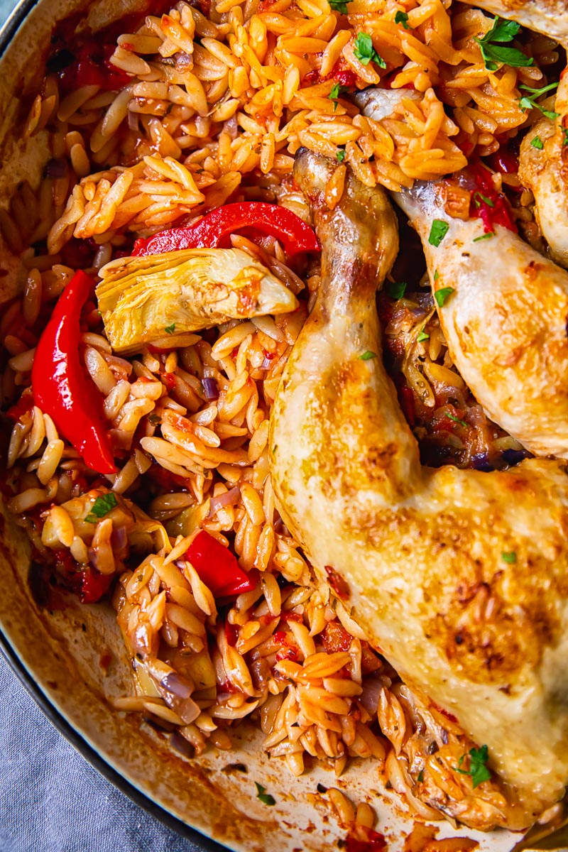 top down view of orzo in a pan with chicken legs.