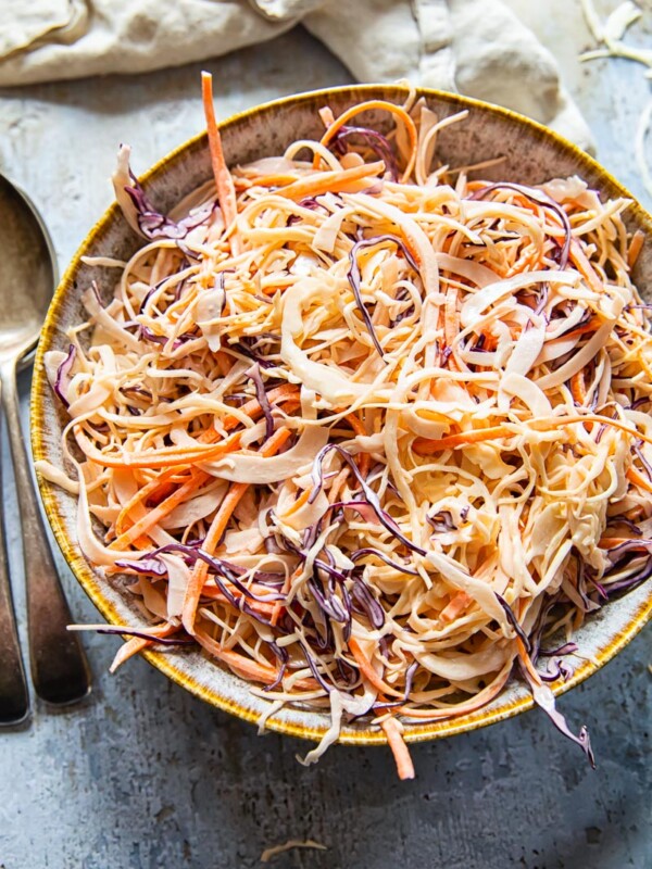 top down view of coleslaw in a bowl, a spoon and napkin.