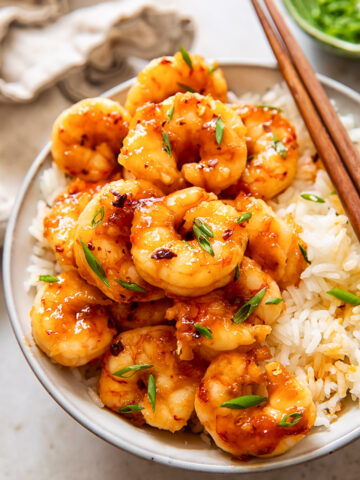 glazed shrimp on top of rice in a bowl.
