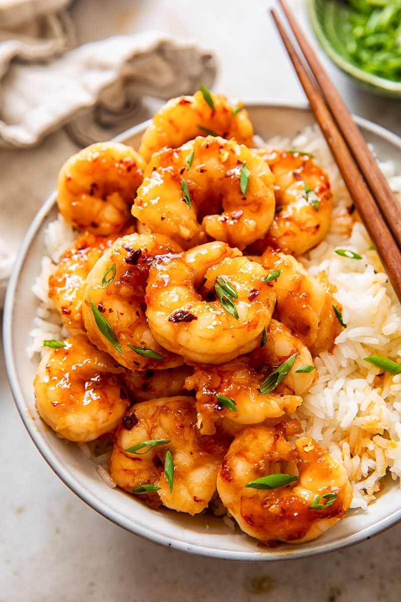 glazed shrimp on top of rice in a bowl.