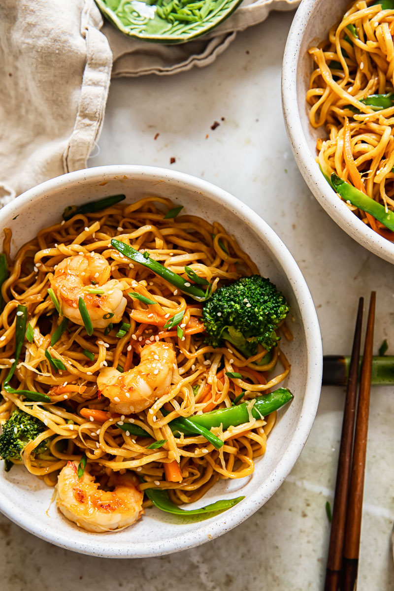 shrimp chow mein in a bowl, chopsticks, cream coloured napkin