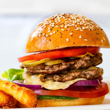 side view smash burger with sliced tomatoes, pickles and lettuce