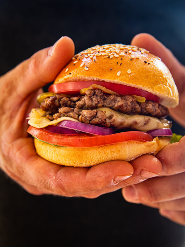 two hands holding a burger