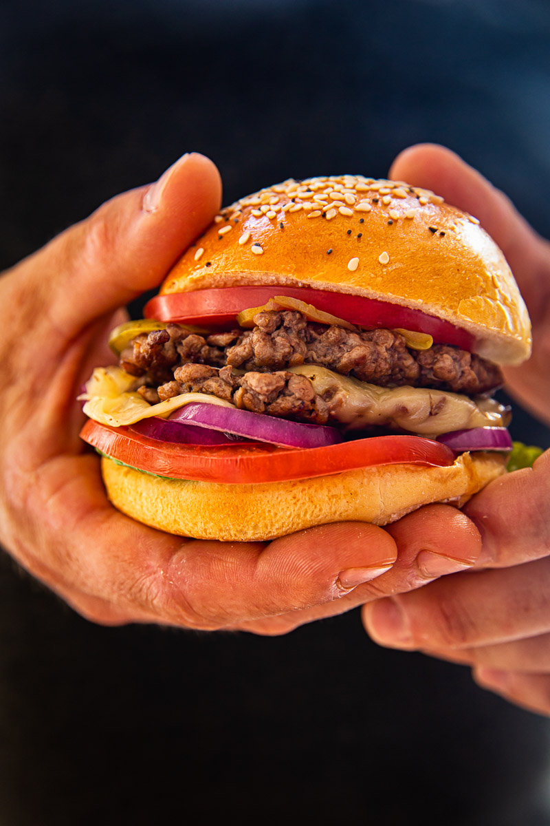 two hands holding a burger