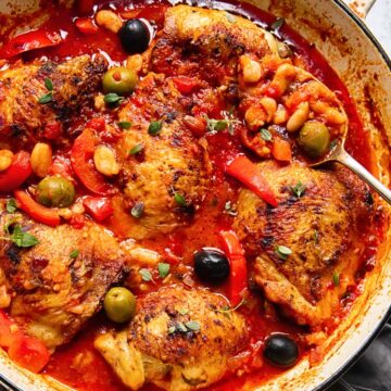 Chicken with red peppers, olives and white beans in a tomato sauce in a pan