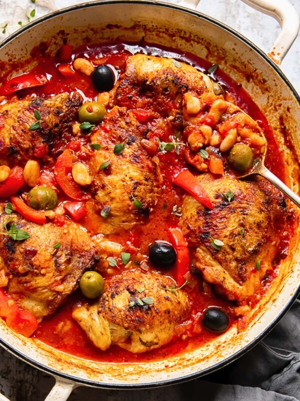 Chicken with red peppers, olives and white beans in a tomato sauce in a pan