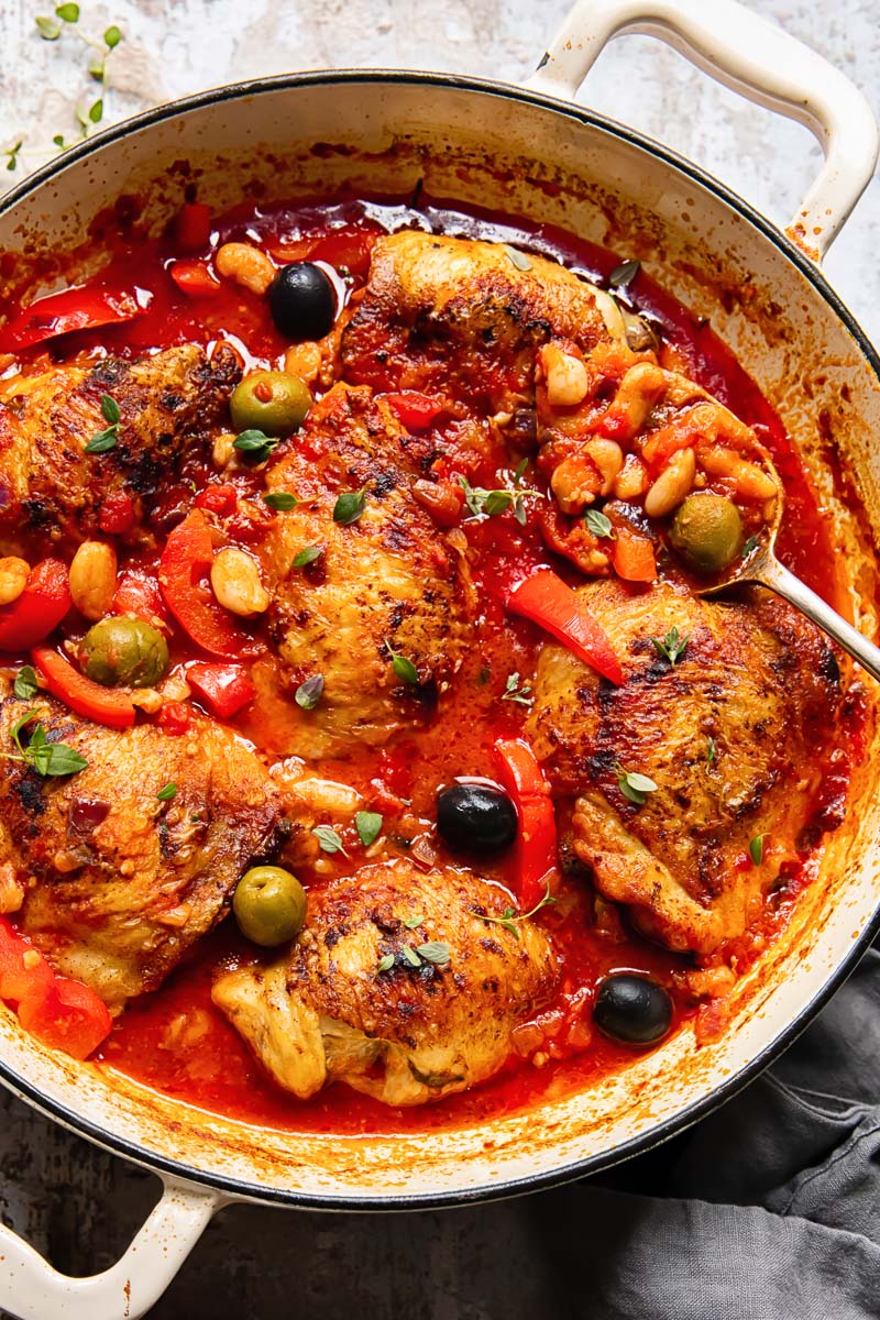 Chicken with red peppers, olives and white beans in a tomato sauce in a pan