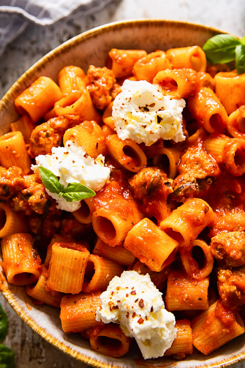 top down view of rigatoni with sausage in tomato sauce topped with ricotta