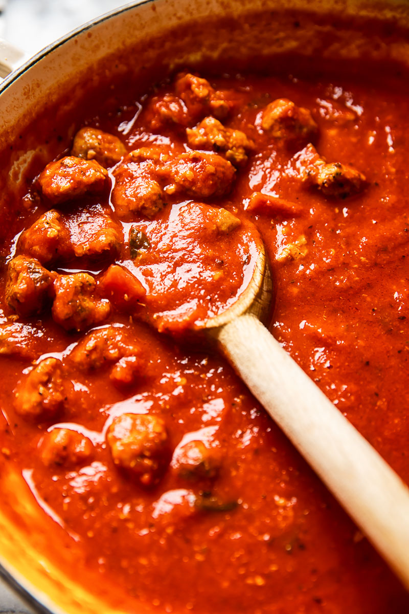 sausage pasta sauce in a pan with a wooden spoon