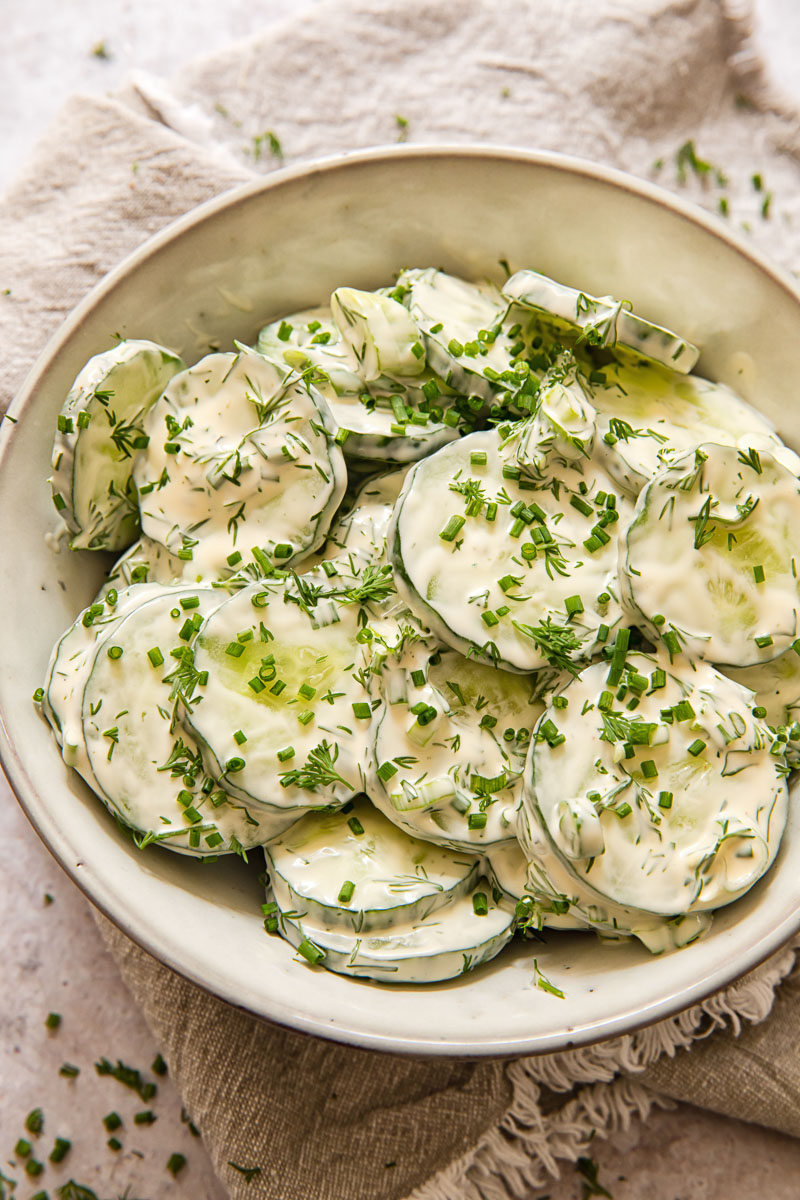 top down view of cucumber salad in creamy dressing in a grey bow;