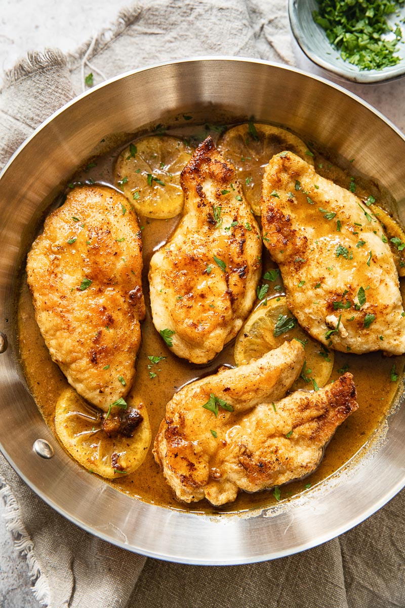 chicken in sauce in a pan, chopped parsley in a small pan