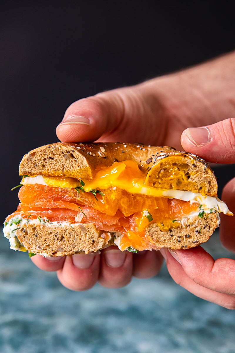 cross section of a bagel sandwich filled with cream cheese, smoked salmon and fried egg