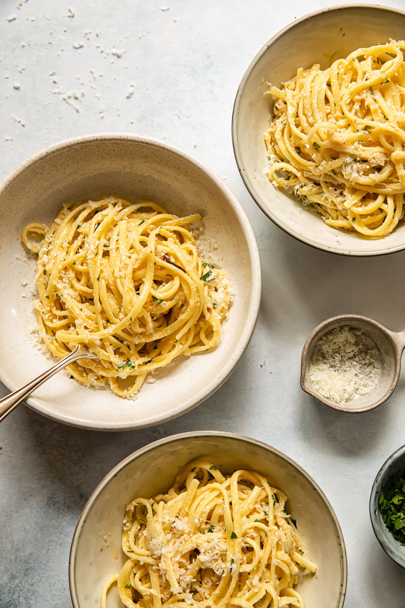 top down view of linguine in three cream coloured bowls