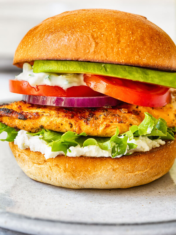 side view of grilled chicken burger with lettuce, onion, tomato and avocado