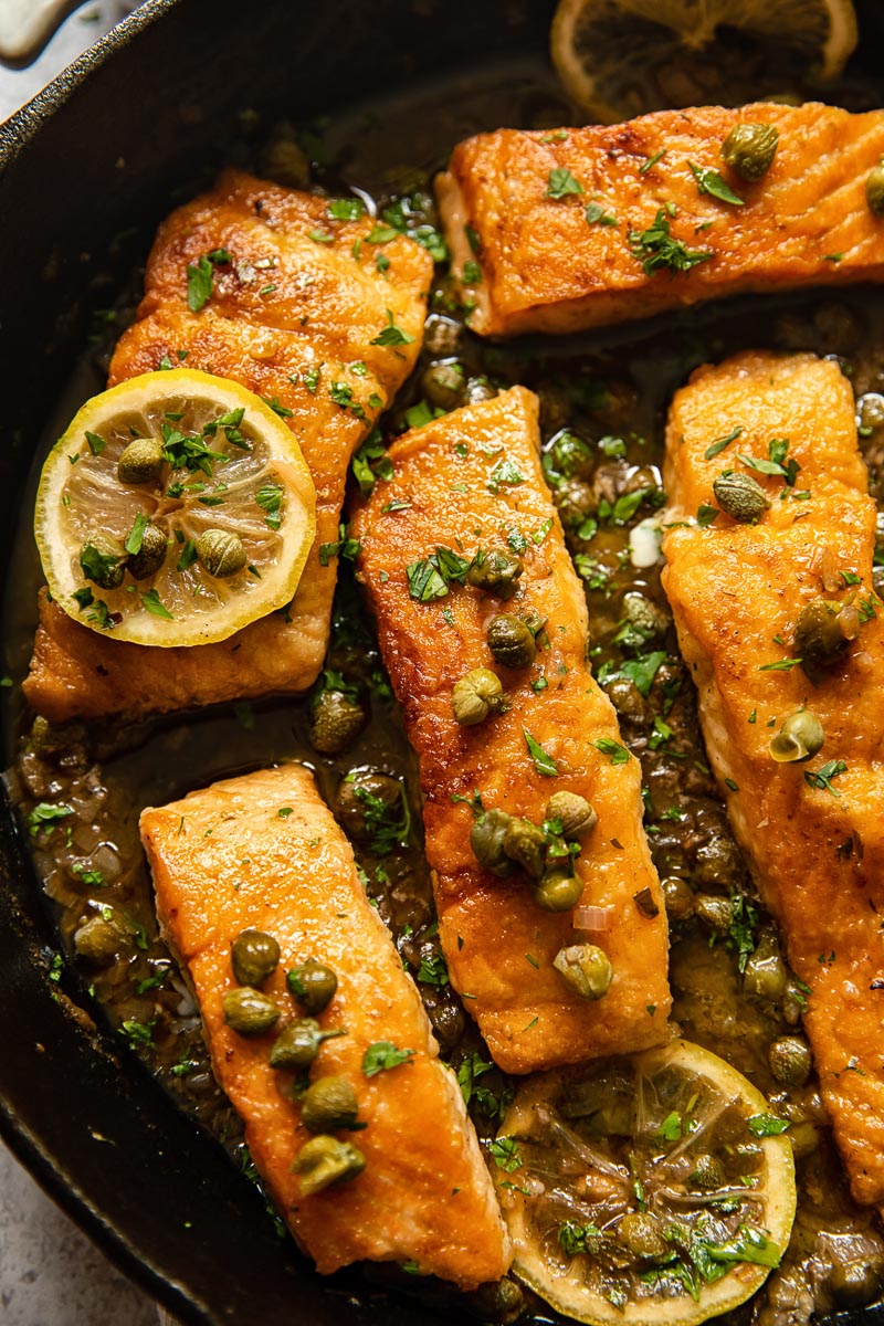 close up of salmon piccata in a cast iron pan