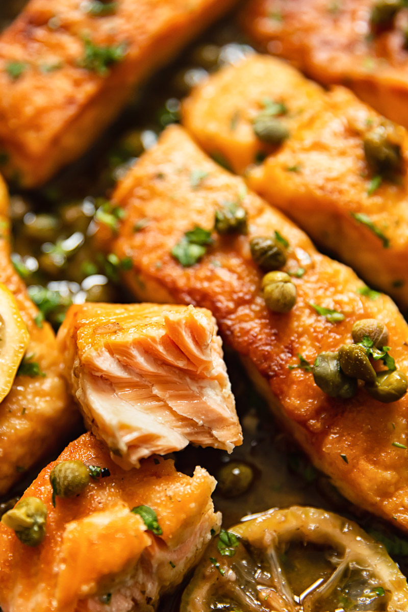 close up of salmon pieces topped with capers and parsley