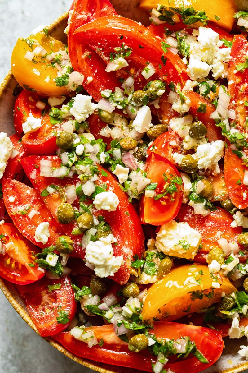 close up of tomato salad with herbs and feta