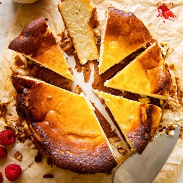 top down view of cheesecake cut into slices, a knife, raspberry compote