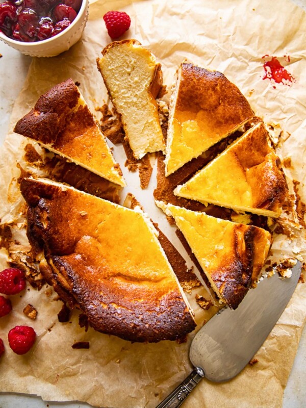 top down view of cheesecake cut into slices, a knife, raspberry compote