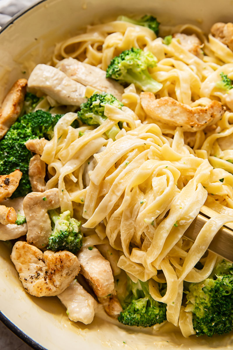 fettuccine in a creamy sauce with chicken and broccoli in a pan