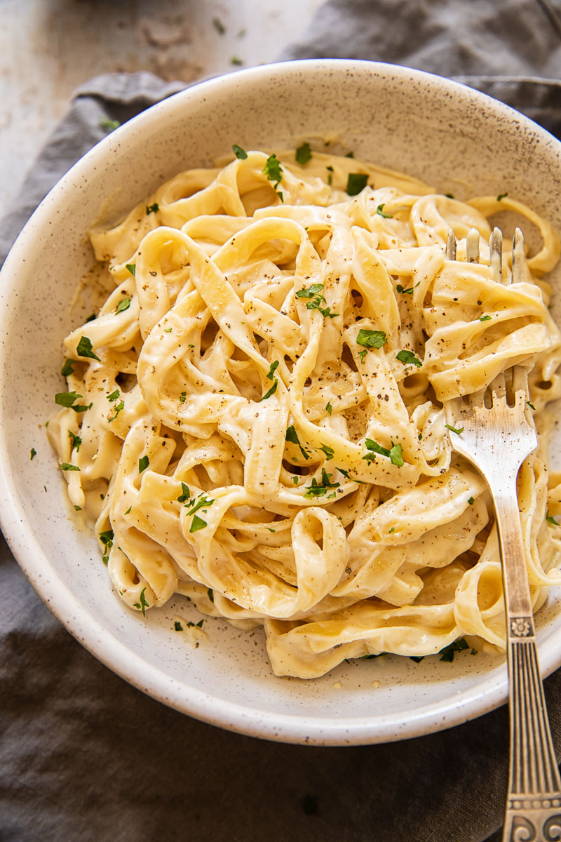 fettuccine alfredo in a bowl sprinkled with fresh parsley