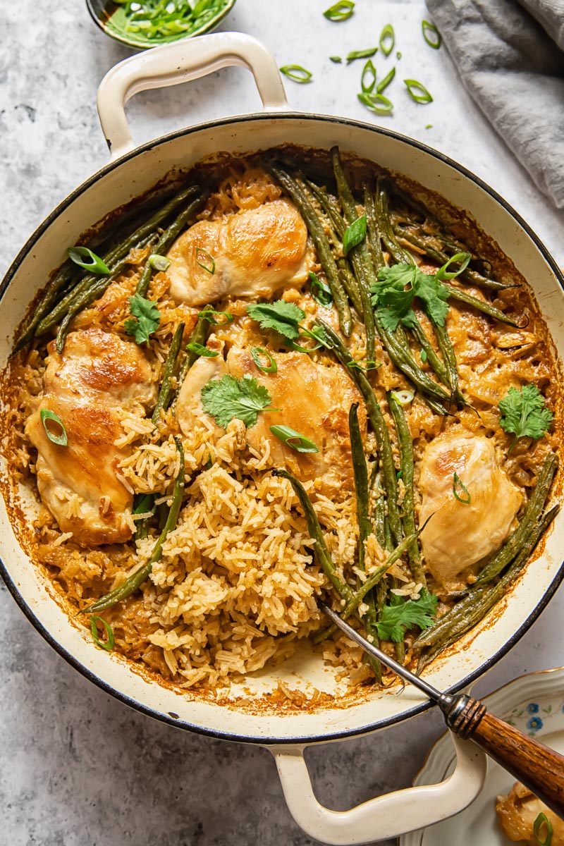 top down view of chicken and rice with green beans in a white pan