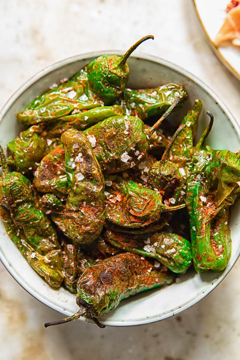 top down view of cooked padron peppers in a bowl