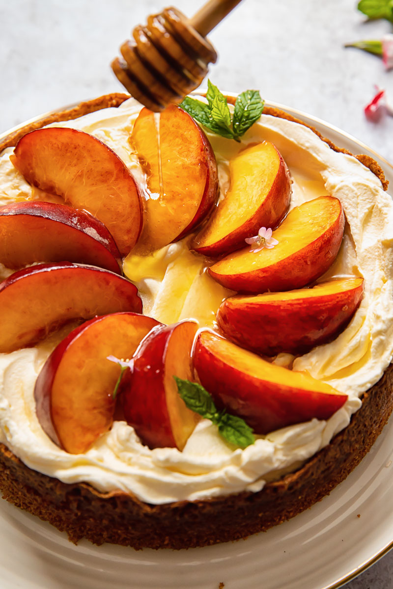 cake topped with whipped cream and sliced peaches, then drizzled with honey