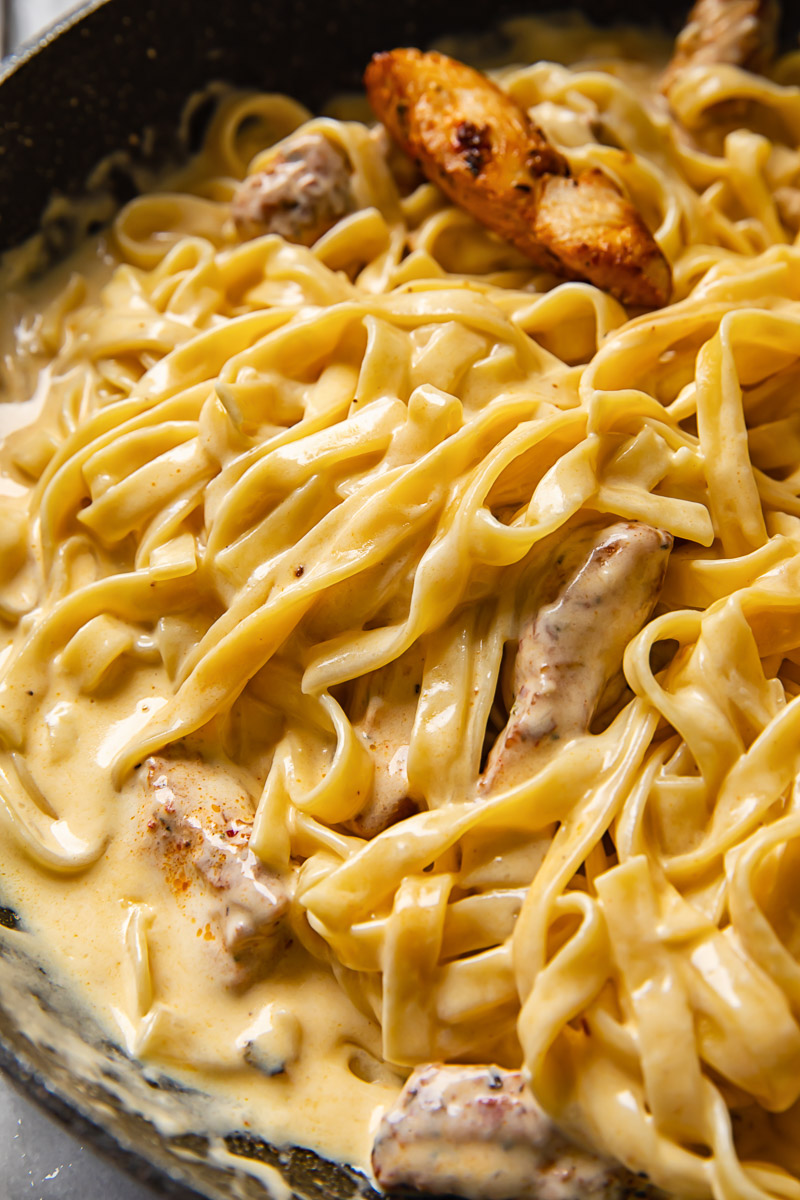 fettuccine in Alfredo sauce with pieces of chicken in a pan