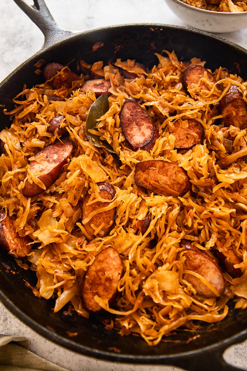 braised sauerkraut with tomatoes and kielbasa in a skillet