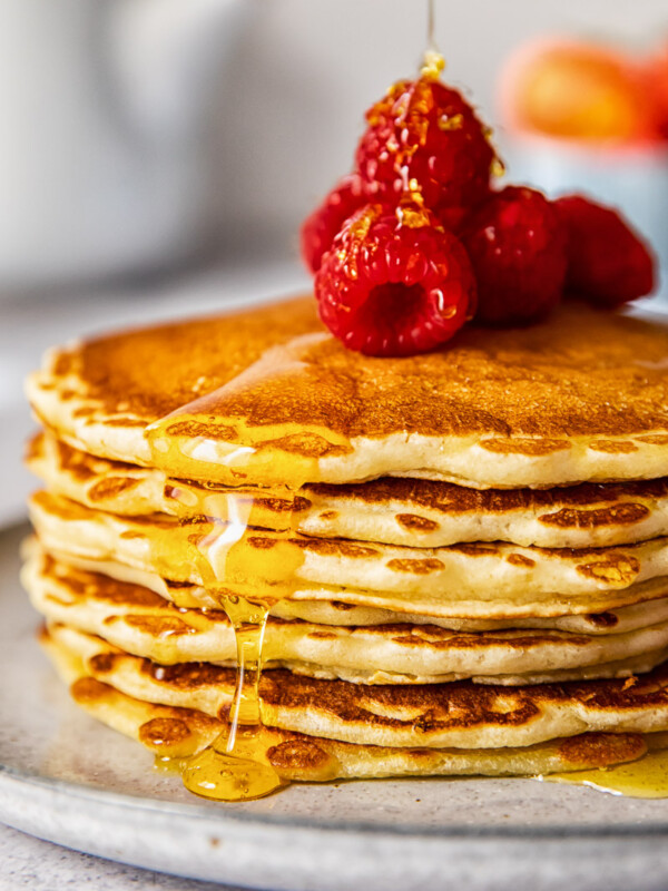 side view of a pancake stack topped with Maple syrup and raspberries