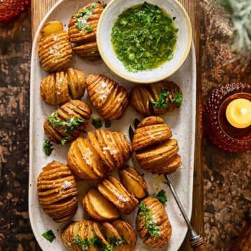 top down view of a platter with roasted potatoes set over a wooden serving board, two candles on the table