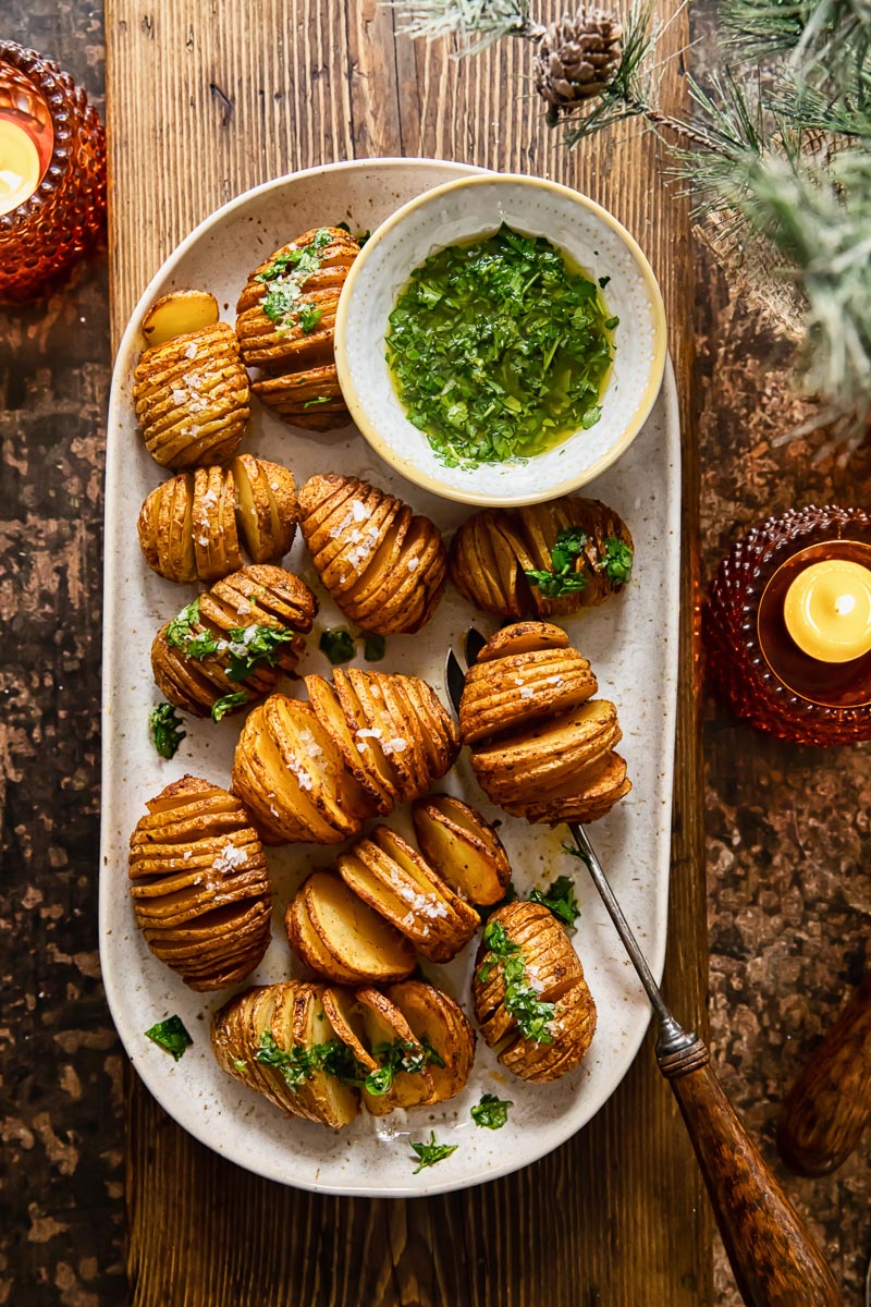 top down view of a platter with roasted potatoes set over a wooden serving board, two candles on the table