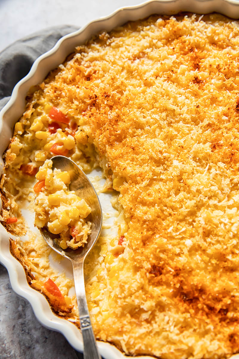 creamy corn bake in a white round dish with a spoon in it