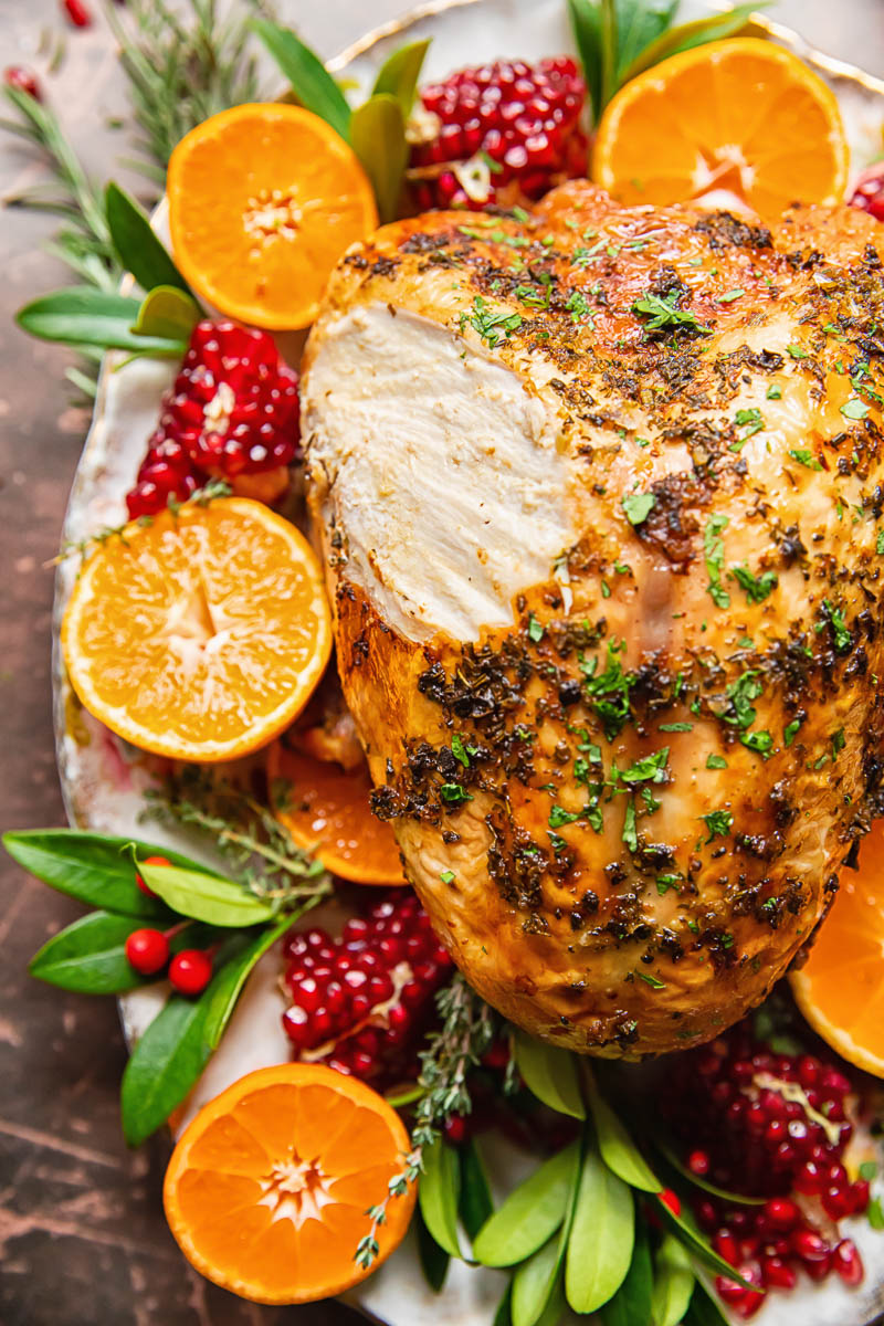 top down view of roast turkey breast garnished with sliced oranges and pomegranates